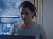 A woman uses a computer in a still from dark obsession