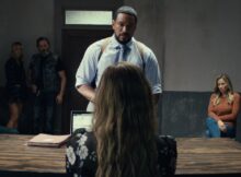 a group of people interrogate a blond woman sitting in a film still from detained