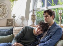 Two teenagers cry while sitting on a couch in fine young men