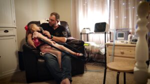 Willow's father helps her use a nebulizer in the film The Zebra and the Bear